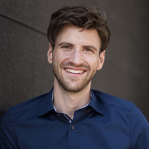 Portrait Of Smiling Businessman At A Wall EBLVKY2